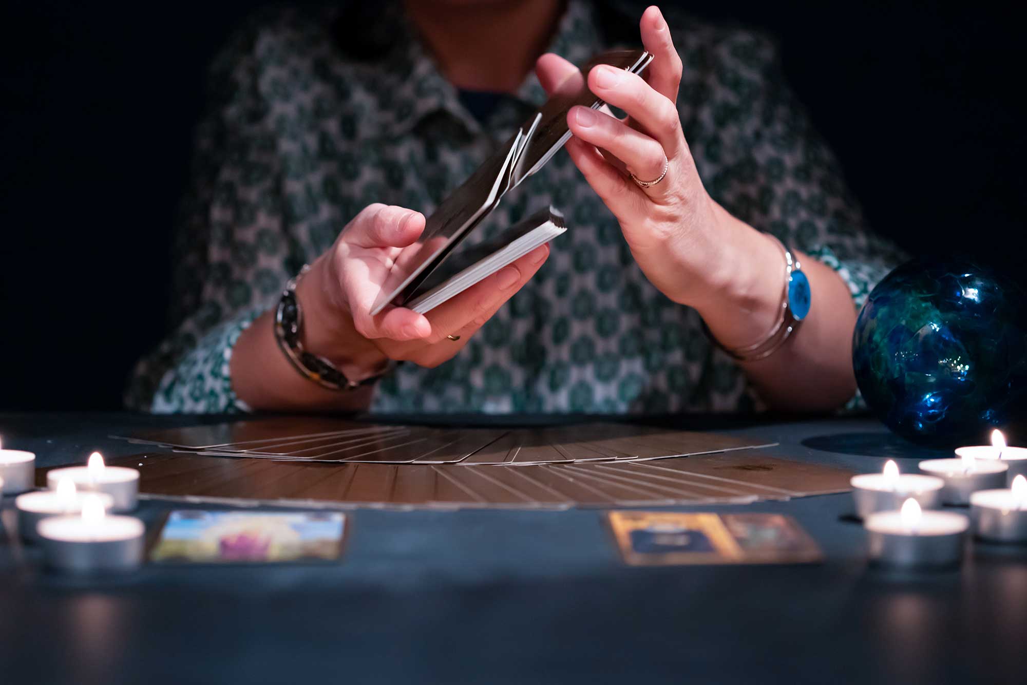 A psychic holding tarot cards during a reading session.
